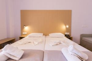 twee bedden in een kamer met witte handdoeken erop bij Atlantis Hotel in Karpathos