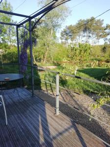 een houten terras met een tafel en een hek bij Les Glycines de Soubize in Lablachère