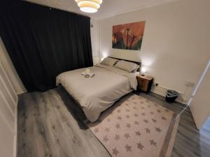a bedroom with a white bed with a black curtain at Cosy 2 Bedroom flat in Grays in Grays Thurrock