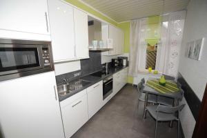 a kitchen with white cabinets and a table with chairs at Ferienwohnung Sabath, 15105 in Leer