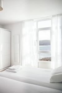 Dormitorio blanco con cama y ventana abierta en Hotel Mar de Fisterra, en Finisterre