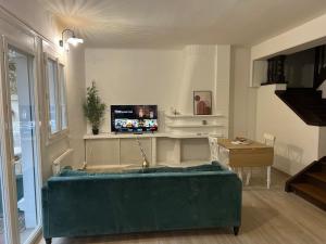 a living room with a green couch and a tv at Charmant Cocon en duplex avec jardin in Noisy-le-Sec