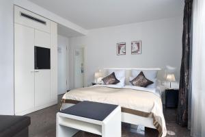 ein weißes Schlafzimmer mit einem weißen Bett und einem TV in der Unterkunft TRIP INN Kaiser Hotel & Restaurant Heidelberg-Schriesheim in Schriesheim