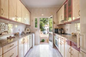 a large kitchen with wooden cabinets and a large window at Villa Amelia - PlusHolidays in Calpe