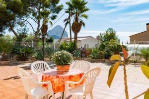 a table with white chairs and a potted plant on it at Villa Amelia - PlusHolidays in Ifach