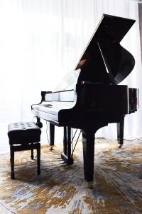 a black piano in a room with a chair at CARD Hôtel in Paris