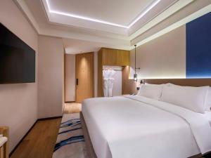 un grande letto bianco in una camera d'albergo di Novotel Shanghai JingAn a Shanghai