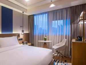 Novotel Shanghai JingAn في شانغهاي: غرفه فندقيه بسرير وكرسي ونافذه