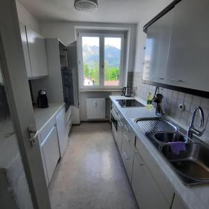 eine Küche mit weißen Schränken, einem Waschbecken und einem Fenster in der Unterkunft Allgäu Auszeit in Sonthofen
