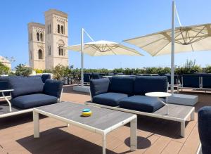 a patio with couches and a table and a clock tower at DOGANA RESORT in Molfetta