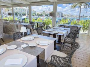 a restaurant with tables and chairs with a view of the water at DOGANA RESORT in Molfetta