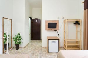 a room with a tv on the wall and a table at Suítes VerdeMar Pereque-Açu in Ubatuba
