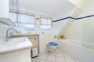 a white bathroom with a tub and a toilet and a sink at Haus Tinchen in Westerland (Sylt)