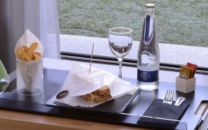 a tray with a sandwich and fries and a bottle of wine at NH Córdoba Urbano in Córdoba