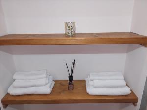 a wooden shelf with three towels and a vase at Novi Outlet Apartment in Novi Ligure +14 photos