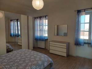 1 dormitorio con 1 cama, 2 ventanas y espejo en Novi Outlet Apartment en Novi Ligure