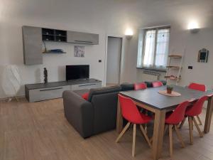 ein Wohnzimmer mit einem Sofa und einem Tisch mit roten Stühlen in der Unterkunft Novi Outlet Apartment in Novi Ligure