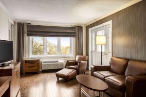 a living room with a couch and chairs and a television at Atlantic Host Hotel, Trademark Collection by Wyndham in Bathurst