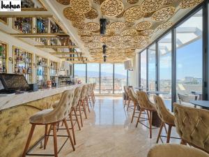 a bar with chairs and tables and windows at NYX Esperia Palace Hotel Athens by Leonardo Hotels in Athens