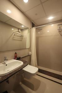 a bathroom with a toilet and a sink and a shower at Hotel Vetro Inn in Surat