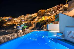 a swimming pool with a view of a city at night at Athina Luxury Suites in Fira
