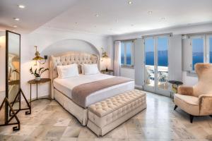 - une chambre avec un grand lit et une chaise dans l'établissement Athina Luxury Suites, à Fira