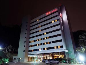 un hotel con coches estacionados en un estacionamiento por la noche en ibis Juiz de Fora en Juiz de Fora