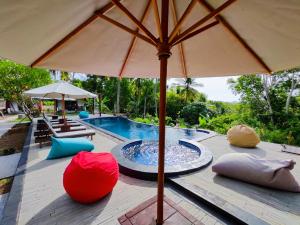 an umbrella sitting on a deck next to a swimming pool at Meket Bungalows in Nusa Penida