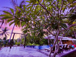 un complejo con piscina, sillas y un árbol en Meket Bungalows, en Nusa Penida