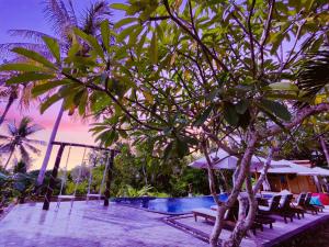 a resort with a pool and chairs and a tree at Meket Bungalows in Nusa Penida