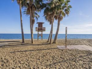 a lifeguard stand on a beach with palm trees at Cubo's Beach Side Apartment at La Cala in La Cala de Mijas
