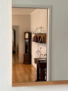 a mirror reflecting a room with a table and a clock at Der Landsitz in Klagenfurt