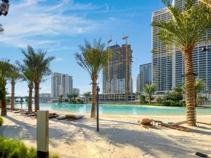 a swimming pool with palm trees and buildings at FAM Living - Vida Residences Stylish 2BR Creekfront Charm in Dubai
