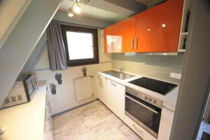 eine kleine Küche mit orangefarbenen Schränken und einem Waschbecken in der Unterkunft Ferienhaus Winnetou Schwarzkittelpfad 85 in Waldbrunn
