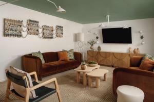 Avante, a JDV by Hyatt Hotel في ماونتن فيو: غرفة معيشة مع أثاث جلدي بني وتلفزيون بشاشة مسطحة