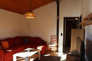 a living room with a red couch and a table at Ferienhaus Robinson Im Abendrot 123 in Waldbrunn