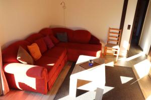 a living room with a red couch and a table at Ferienhaus Robinson Im Abendrot 123 in Waldbrunn
