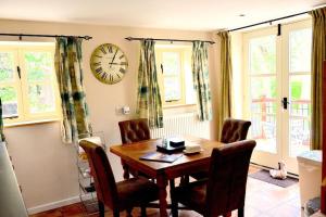 a dining room table with chairs and a clock on the wall at Hafannedd Cottage - riverside views in Corwen
