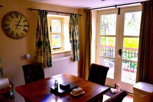 a dining room with a table and a clock on the wall at Hafannedd Cottage - riverside views in Corwen