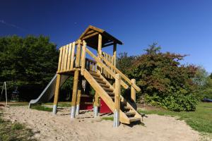 einen Holzspielplatz mit Rutsche im Sand in der Unterkunft Ferienhaus Robinson Paradiesecke 174 in Waldbrunn