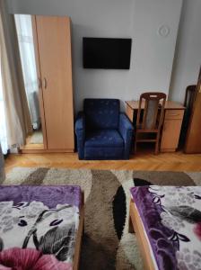 a living room with a blue chair and a tv at Motel BI in Bijeljina