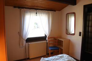 a bedroom with a window and a bed and a chair at Ferienhaus Scout Paradiesecke 179 in Waldbrunn