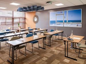 een eetkamer met tafels en stoelen en het strand bij ibis La Baule Pornichet Plage in Pornichet