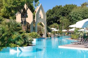 a pool at a resort with chairs and umbrellas at Dionysos Hotel in Ixia