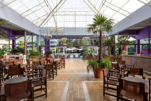 فندق ديونيسوس  في إيكسيا: صالة طعام بها طاولات وكراسي والنخيل