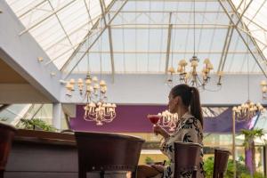 فندق ديونيسوس  في إيكسيا: امرأة تجلس على طاولة مع كوب من النبيذ