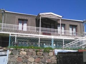 a large house with a large white balcony at Maia's Guest House Gergeti in Kazbegi