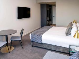 a hotel room with a bed and a table and a tv at Mantra Tonsley Adelaide in Adelaide