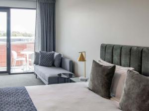 a bedroom with a bed and a couch and a chair at Mantra Tonsley Adelaide in Adelaide