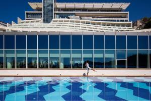 a woman walking in front of a building with a pool at Rixos Premium Dubrovnik in Dubrovnik